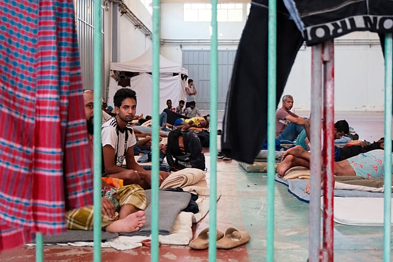 FILE - Migrants, who arrived recently at the island of Crete, are held under guard at a temporary shelter in the village of Agia, Crete, southern Greece, Aug. 19, 2025