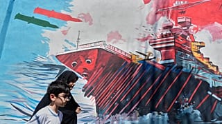 الناس يمرون أمام لوحة جدارية تصور حاملة طائرات أمريكية تتعرض لهجوم صاروخي في وسط مدينة طهران، إيران، الاثنين 8 يونيو 2026.