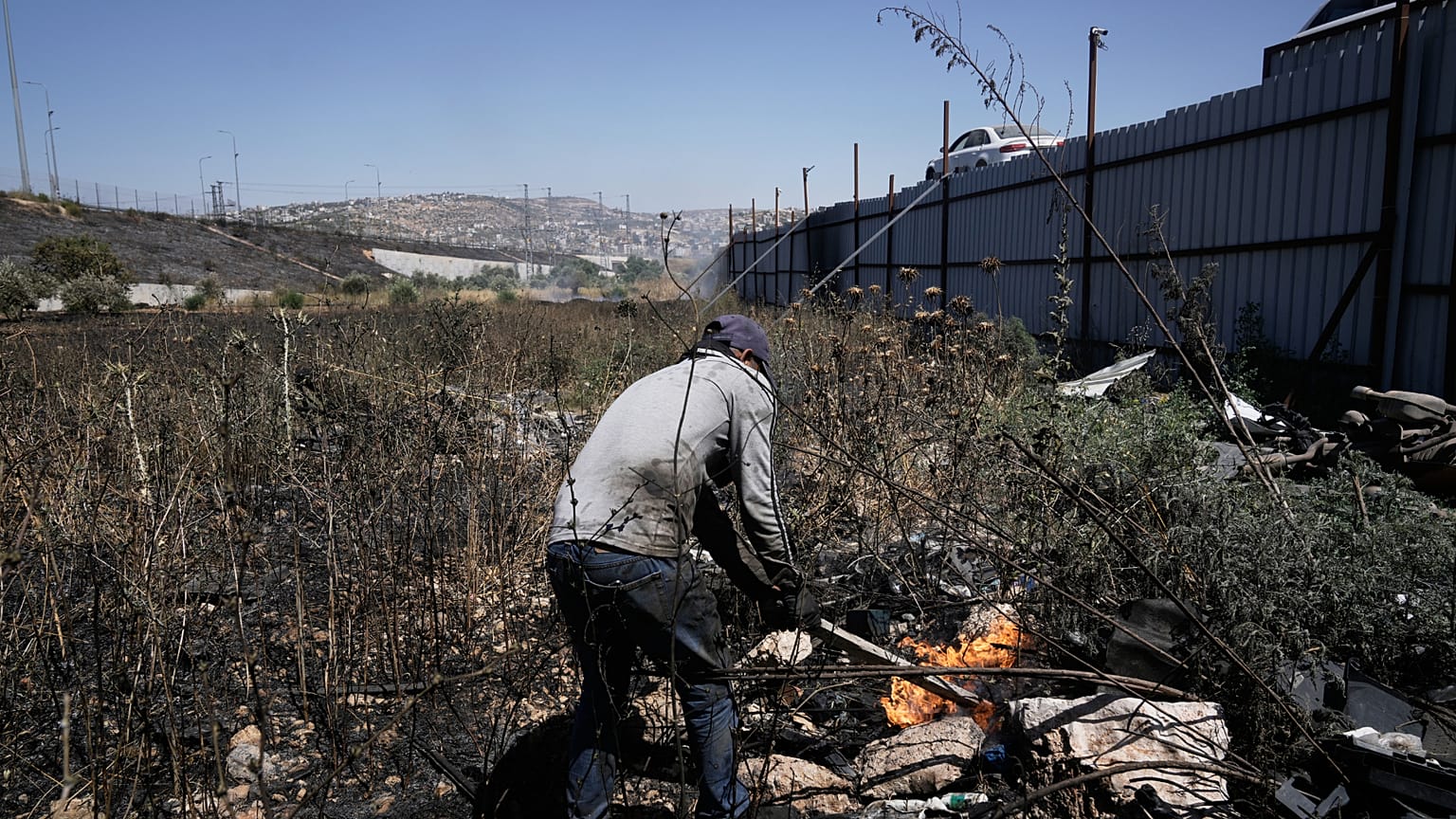 رجل فلسطيني يطفئ حريقا في موقع هجوم المستوطنين الإسرائيليين في بلدة حوارة بالضفة الغربية، نابلس، السبت 6 يونيو 2026. (AP Photo/مجدي محمد)