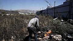 رجل فلسطيني يطفئ حريقا في موقع هجوم المستوطنين الإسرائيليين في بلدة حوارة بالضفة الغربية، نابلس، السبت 6 يونيو 2026. (AP Photo/مجدي محمد)