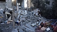 Palesztin fiatalok mentik holmijukat egy épületből, amelyet egy izraeli légicsapás rombolt le az al-Maghazi menekülttáborban.
