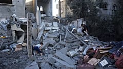 Des jeunes Palestiniens récupèrent leurs affaires dans un immeuble détruit par une frappe israélienne, au camp de réfugiés d’al-Maghazi