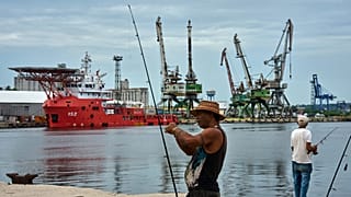 Un pescador prepara su caña de pescar frente al buque de la Armada colombiana ARC Caribe, atracado en un muelle de La Habana, Cuba, tras su llegada con ayuda humanitaria, el 1