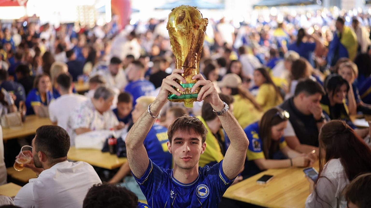Bir Bosnalı taraftar, 12 Haziran 2026'da Saraybosna'daki bir taraftar alanında şişme Dünya Kupası kupasını sallıyor.