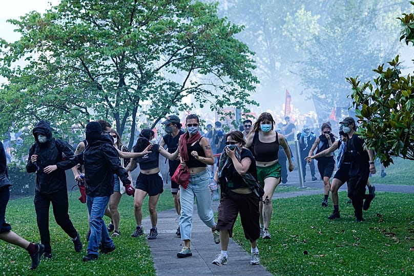 Protesters disperse through a grassy area during a "No G7" demonstration in Geneva, Switzerland, Sunday, June 14, 2026, ahead of the G7 summit scheduled to take place June 15-