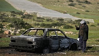 صورة أرشيفية- يتفقد أحد السكان سيارة أضرم فيها مستوطنون إسرائيليون النار، بحسب الهلال الأحمر الفلسطيني، في قرية تياسير بالضفة الغربية، قرب طوباس