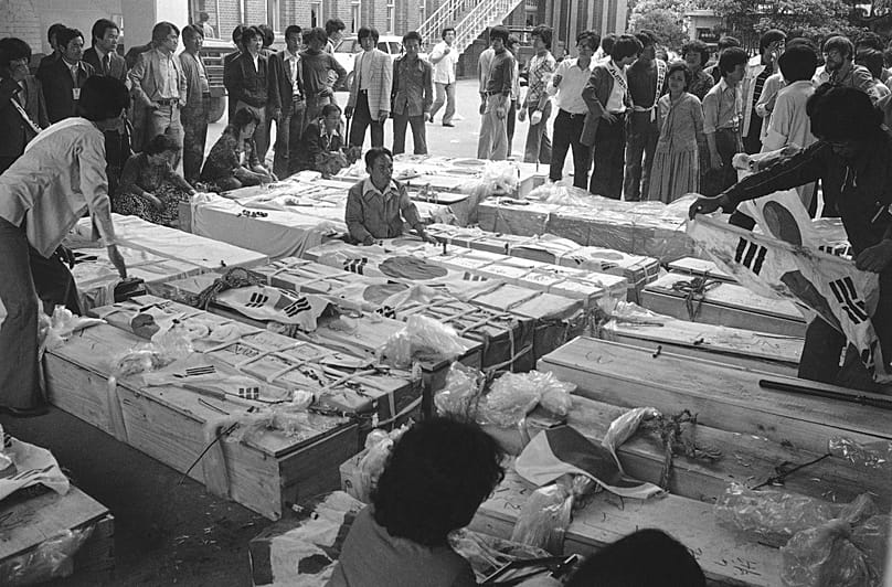 Families and relatives gather around the coffins of dead protesters at provincial headquarters in Gwangju, 23 May, 1980