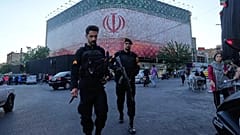 Полицейские проходят перед огромным баннером с изображением флага Ирана на площади Исламской революции в Тегеране, 14 июня 2026 года