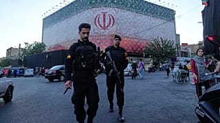 Policemen walk in front of a huge banner showing Iranian flag at the Islamic Revolution square in Tehran, 14 June 2026