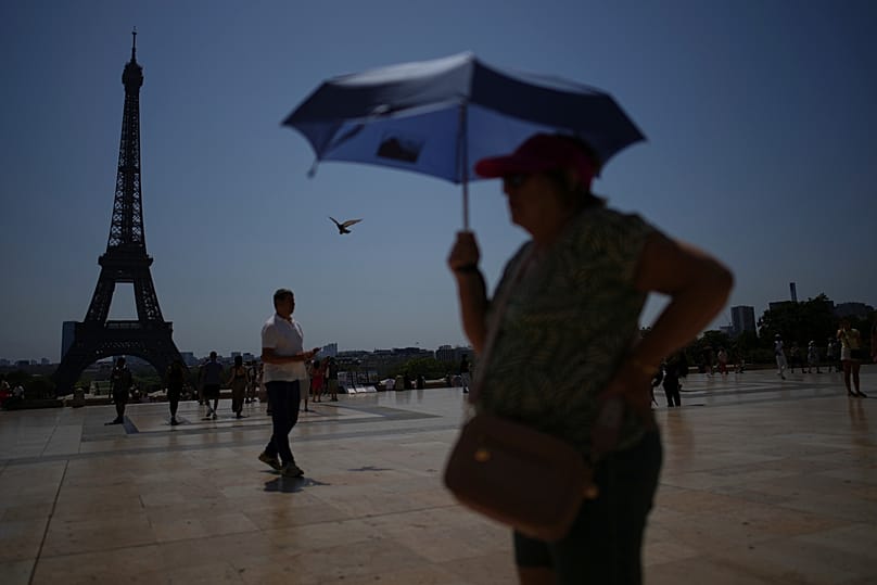 ARQUIVO – Pessoas passeiam na praça do Trocadéro, junto à Torre Eiffel, durante uma onda de calor, em 2 de julho de 2025, em Paris