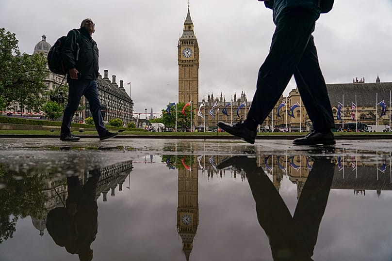 The Elizabeth Tower, commonly known as Big Ben, reflected in a puddle as people walk past in London, 3 June, 2026