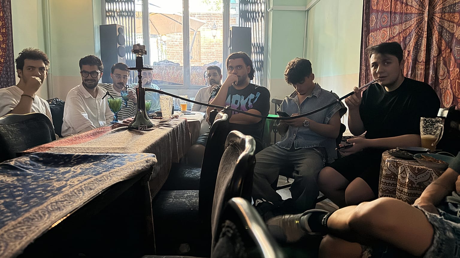 Adeptos iranianos acompanham num café em Teerão o jogo da seleção contra a Nova Zelândia no Mundial, enquanto um fuma um cachimbo de água