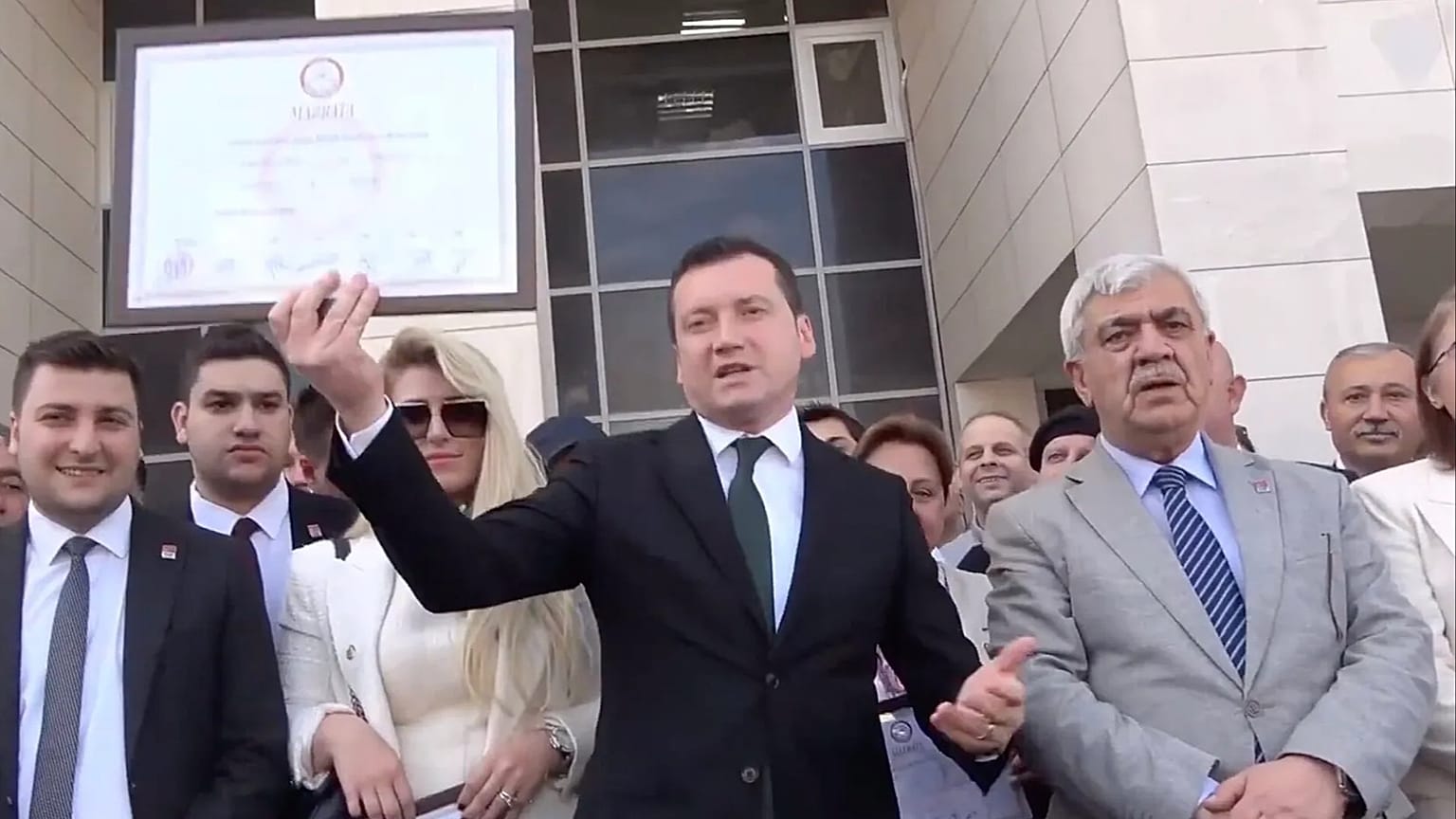 Silivri Belediye Başkanı Bora Balcıoğlu (ortada) 2024 seçimlerinin ardından belediye binasının girişinde mazbatasını tutarken