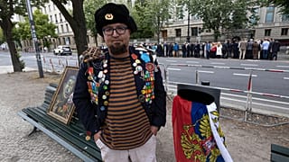 Semyon Skrepetsky posa para uma fotografia com um dos seus quadros junto à Embaixada da Rússia em Berlim, a 12 de junho de 2026
