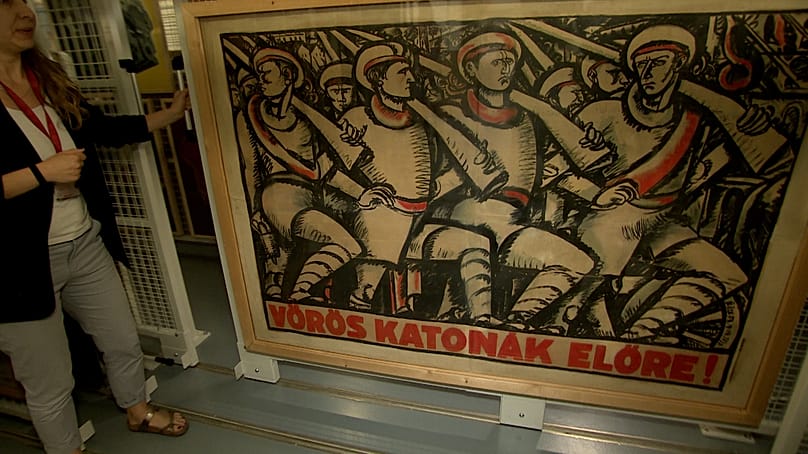 Katona Anikó propagandaplakátokat mutat a Magyar Nemzeti Galéria egy gyűjteményében