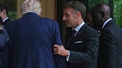 Emmanuel Macron tient le bras de Donald Trump après une photo de groupe des dirigeants lors du sommet du G7, mardi 16 juin 2026, à Évian-les-Bains, en France.