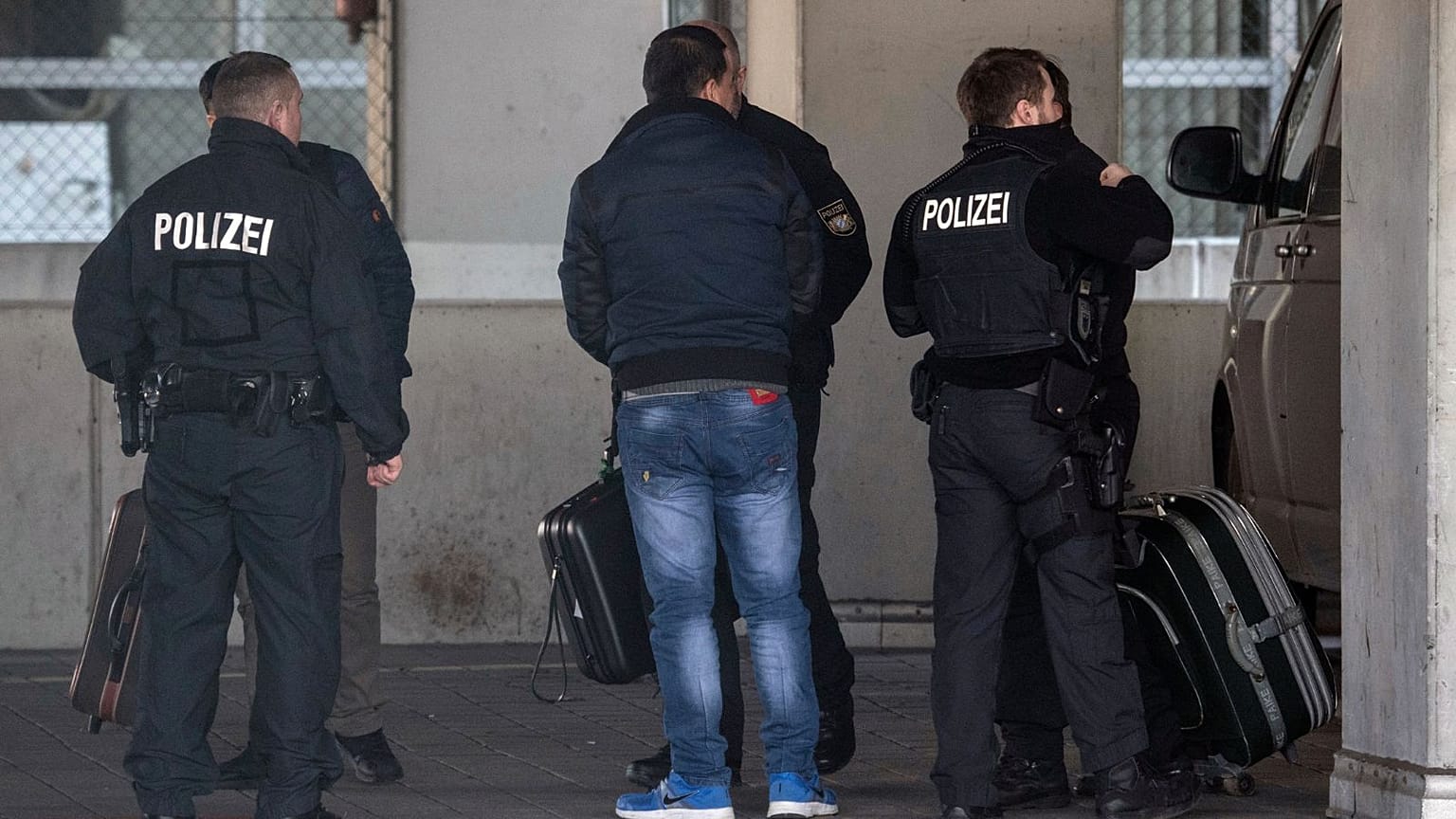 German police officers accompany a man to an airport terminal, from where he is to be deported to Afghanistan, with a chartered plane in Frankfurt, Germany