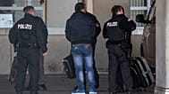 German police officers accompany a man to an airport terminal, from where he is to be deported to Afghanistan, with a chartered plane in Frankfurt, Germany