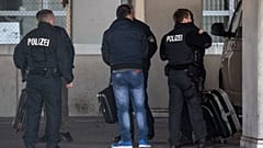 German police officers accompany a man to an airport terminal, from where he is to be deported to Afghanistan, with a chartered plane in Frankfurt, Germany