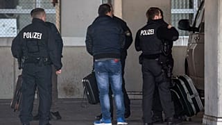 German police officers accompany a man to an airport terminal, from where he is to be deported to Afghanistan, with a chartered plane in Frankfurt, Germany
