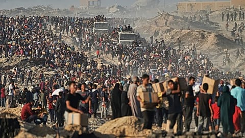 Palestinos cargan sacos y cajas de alimentos y ayuda humanitaria descargados de un convoy del Programa Mundial de Alimentos cerca de Ciudad de Gaza, 16 de junio de 2025