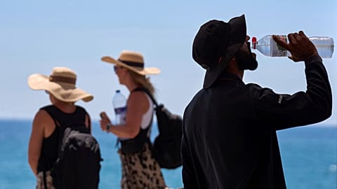  A tourist drinks water on a hot day at the beach in Barcelona, Spain, July 2, 2025.