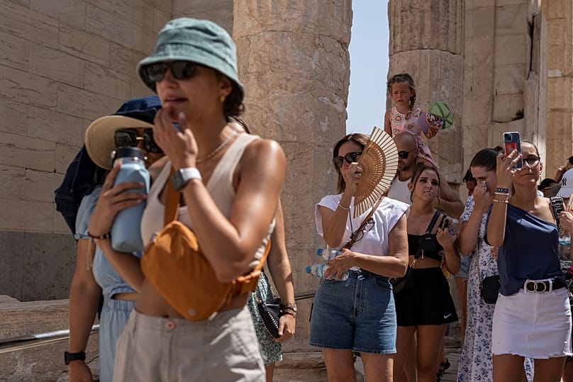 سياح يتجولون في تلة الأكروبوليس القديمة أثناء موجة حر في أثينا، اليونان، 21 يوليو/تموز 2023.