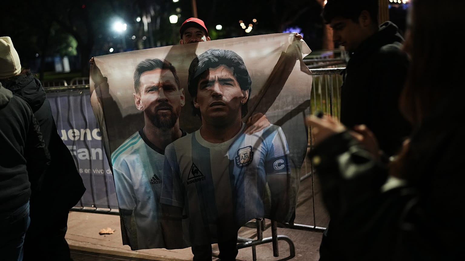 A fan holds a poster of soccer stars Lionel Messi and Diego Maradona after watching the World Cup soccer match between Argentina and Algeria in Buenos Aires,
