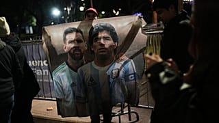 A fan holds a poster of soccer stars Lionel Messi and Diego Maradona after watching the World Cup soccer match between Argentina and Algeria in Buenos Aires,