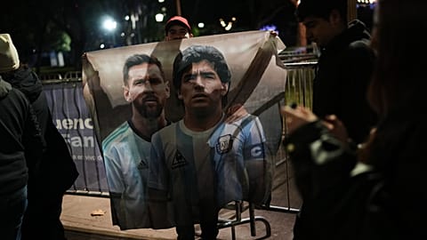 A fan holds a poster of soccer stars Lionel Messi and Diego Maradona after watching the World Cup soccer match between Argentina and Algeria in Buenos Aires,