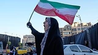 امرأة تلوح بالأعلام الإيرانية وهي تهتف بشعارات ضد المحادثات الإيرانية والأمريكية في ساحة الثورة الإسلامية في طهران، إيران، الأحد 14 يونيو 2026. 