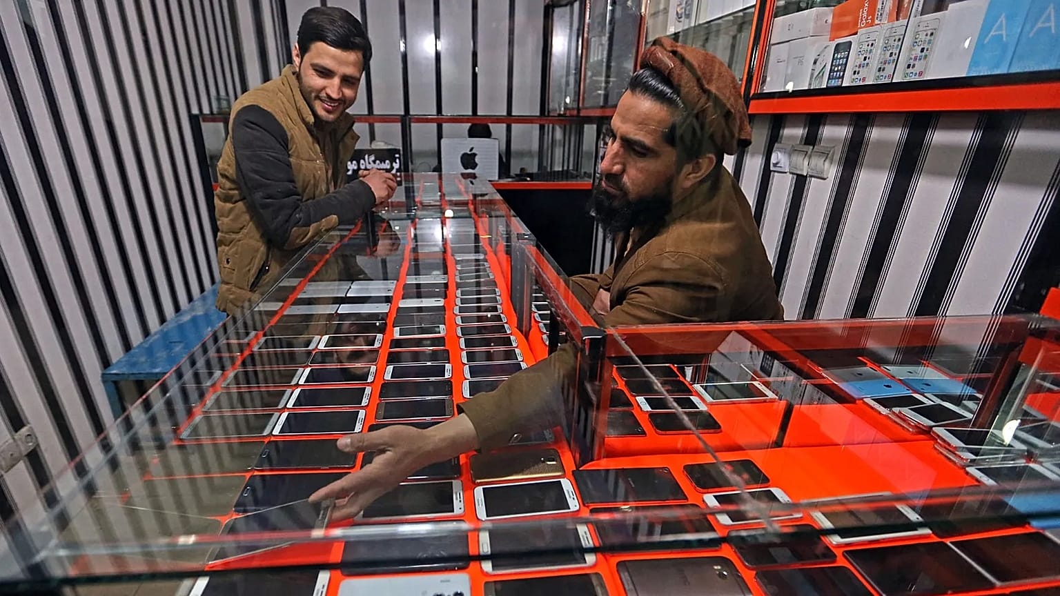 An Afghan shopkeeper shows a smartphone to a customer in Kabul, 12 February, 2016