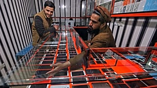 An Afghan shopkeeper shows a smartphone to a customer in Kabul, 12 February, 2016