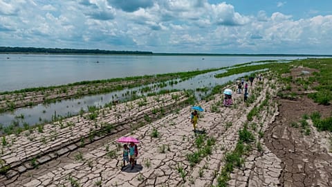 People walk through a part of the Amazon River that shows signs of drought in Santa Sofia, on the outskirts of Leticia, Colombia, Oct. 20, 2024. 