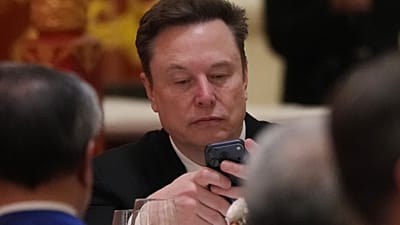 Elon Musk utilise son téléphone lors d'un dîner d'État pour le président Donald Trump et le président chinois Xi Jinping au Grand Palais du Peuple, jeudi 14 mai 2026, à Pékin