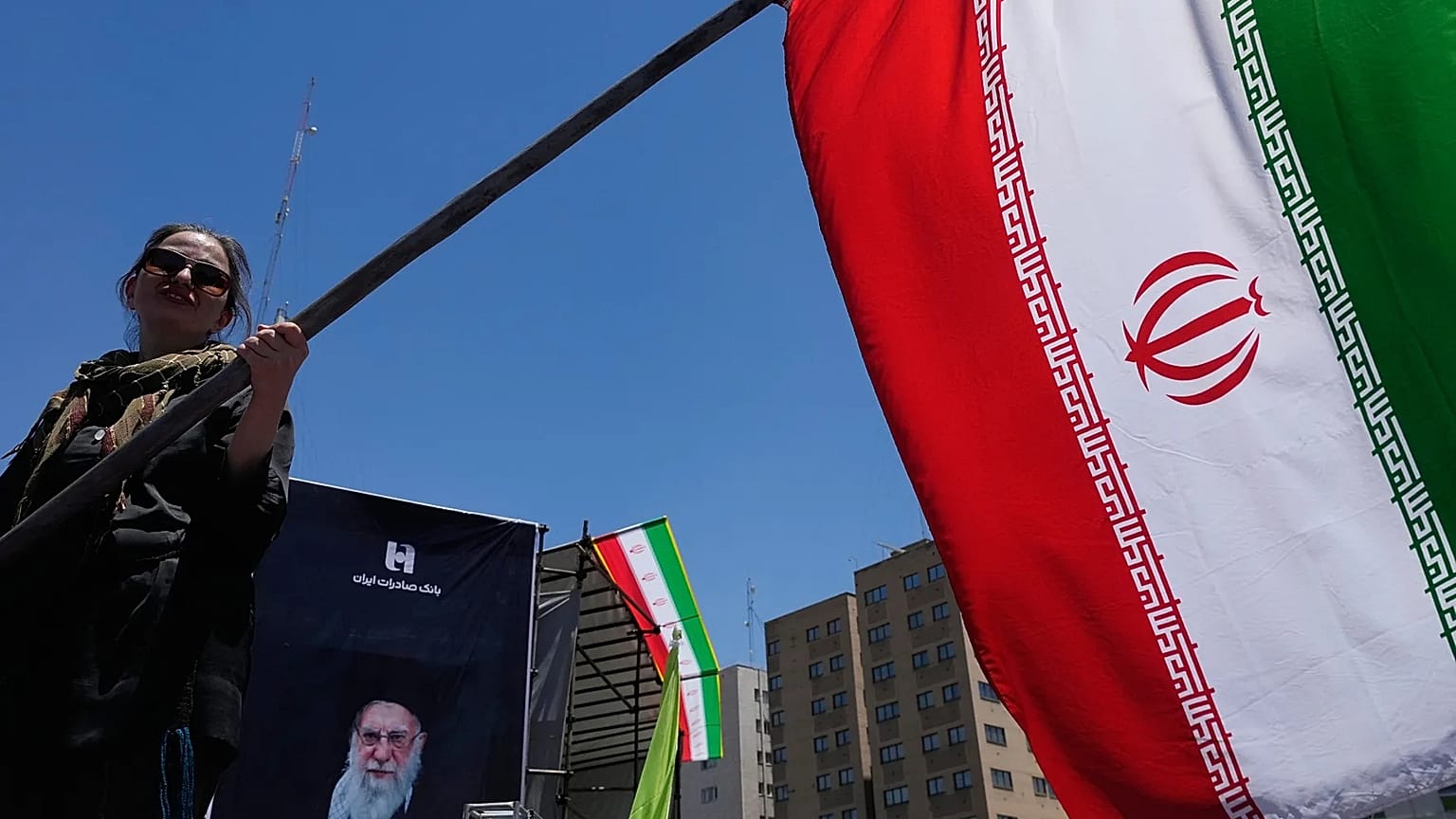 Una donna sventola una bandiera iraniana durante una campagna filogovernativa nel centro di Teheran, 15 giugno 2026.