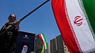 A woman waves an Iranian flag during a pro-government campaign in downtown Tehran, 15 June, 2026