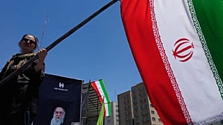 A woman waves an Iranian flag during a pro-government campaign in downtown Tehran, 15 June, 2026