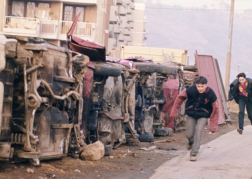 Due giovani bosniaci cercano riparo dai cecchini dietro carcasse di auto nel quartiere Dobrinja di Sarajevo nel 1993
