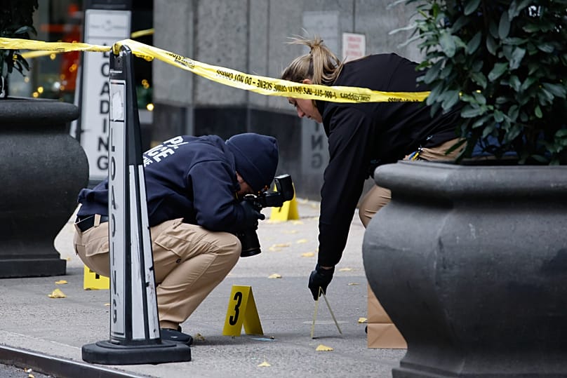 Members of the New York police investigate the scene outside the Hilton Hotel in midtown Manhattan, 4 December, 2024