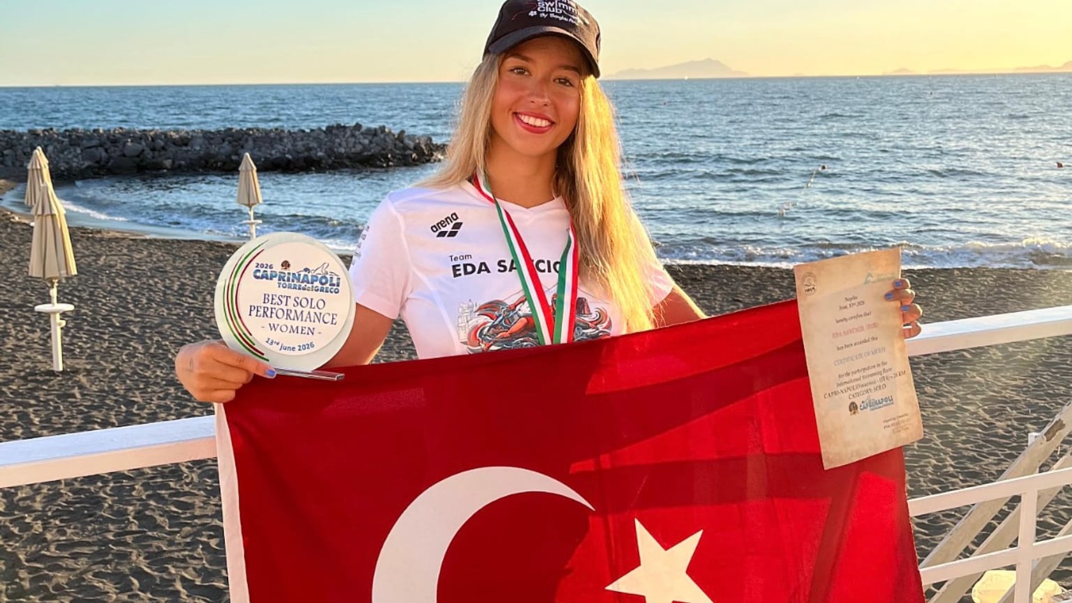 İtalya'da elde ettiği tarihi başarının ardından milli yüzücü Eda Savcıgil, Türk bayrağı ile poz veriyor.