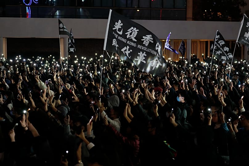 Protesters hold up their smartphone lights and their hands to symbolise the five demands of the pro-democracy movement in Hong Kong, 23 December, 2019