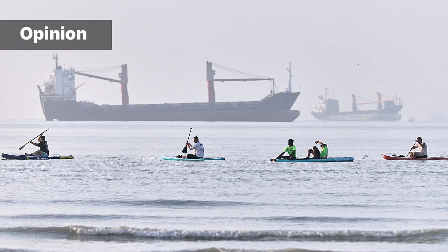 People paddle along the shoreline as cargo ships are anchored in the Strait of Hormuz off Bandar Abbas, Iran, Monday, June 1, 2026. (Amirhosein Khorgooi/ISNA via AP)
