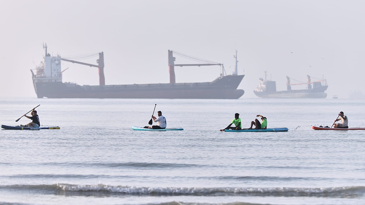 People paddle along the shoreline as cargo ships are anchored in the Strait of Hormuz off Bandar Abbas, Iran, Monday, June 1, 2026. (Amirhosein Khorgooi/ISNA via AP)