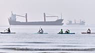 People paddle along the shoreline as cargo ships are anchored in the Strait of Hormuz off Bandar Abbas, Iran, Monday, June 1, 2026. (Amirhosein Khorgooi/ISNA via AP)