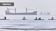 People paddle along the shoreline as cargo ships are anchored in the Strait of Hormuz off Bandar Abbas, Iran, Monday, June 1, 2026. (Amirhosein Khorgooi/ISNA via AP)