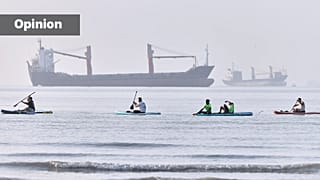 People paddle along the shoreline as cargo ships are anchored in the Strait of Hormuz off Bandar Abbas, Iran, Monday, June 1, 2026. (Amirhosein Khorgooi/ISNA via AP)