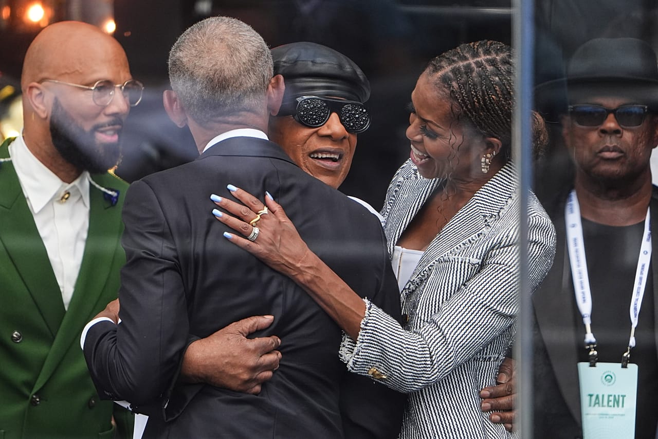From left: Common, former President Barack Obama and former first lady Michelle Obama embrace Stevie Wonder.