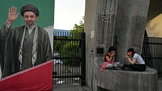 Women smoke cigarettes next to a portrait of the Iranian Supreme Leader Ayatollah Mojtaba Khamenei in Tehran, 12 May, 2026