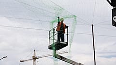 In Saporischschja in der Ukraine installiert ein städtischer Arbeiter ein Anti-Drohnen-Netz, um Menschen und Verkehr vor russischen Angriffen zu schützen.